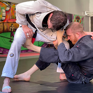 Dva BJJ praktikanta v kimonu izvajata borilno veščino jiu jitsu.